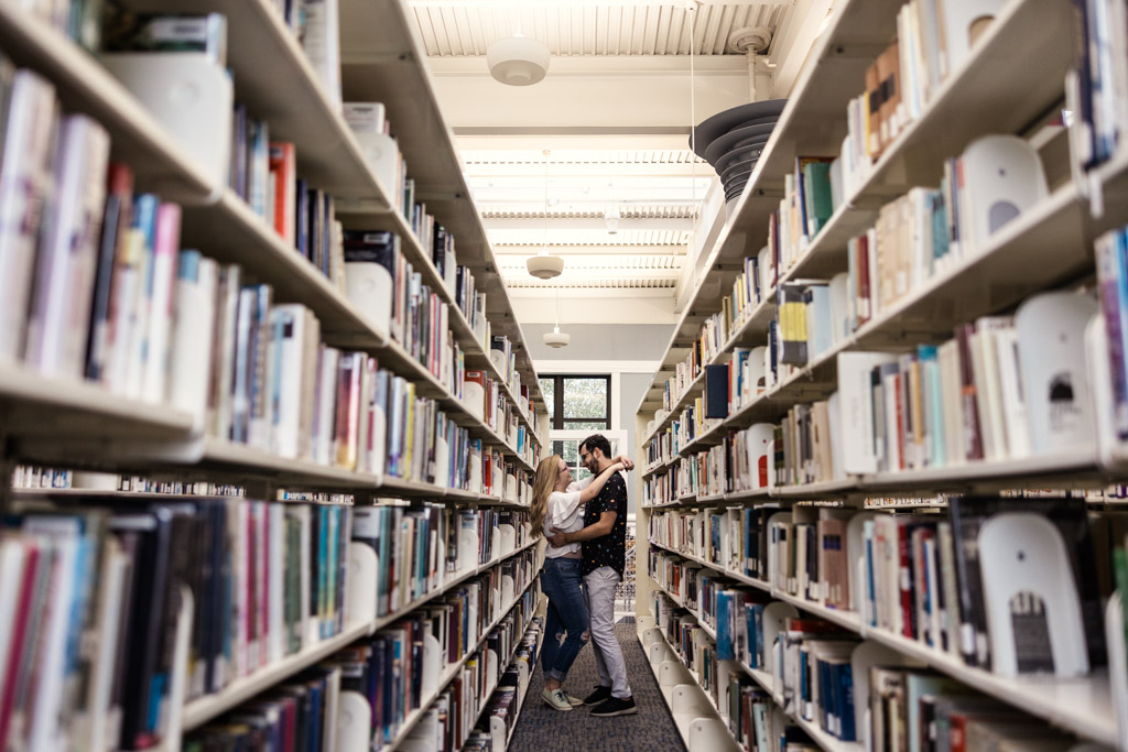 Couple gets cozy between rows of books at local library during Lincoln Square engagement session