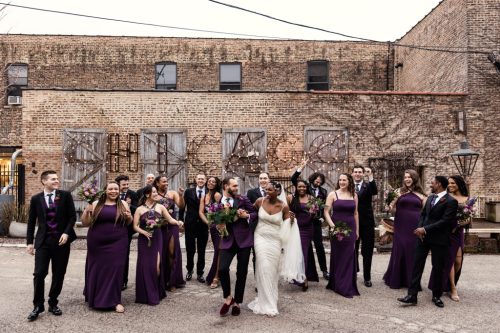 Candid photo of wedding party walking by Chicago sign at Salvage One wedding