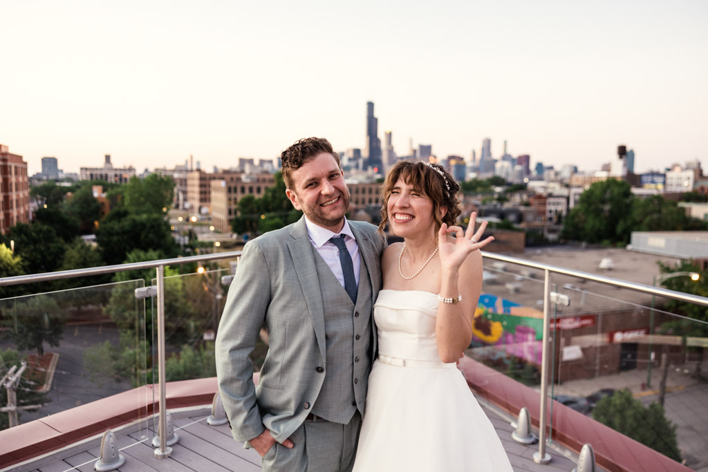 Just married bride and groom smile on rooftop with Chicago skyline at Lacuna Lofts in Pilsen