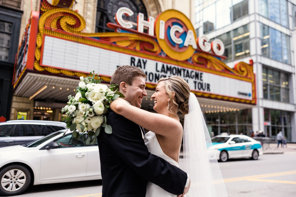 Bride and groom smile outside of Chicago Theater at their downtown wedding at ROOF on theWit
