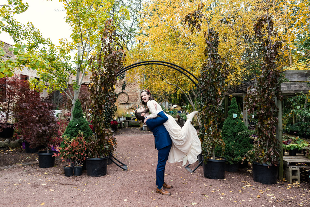 Fun photo of groom lifting bride at their fall Blumen Gardens wedding in Sycamore, Illinois