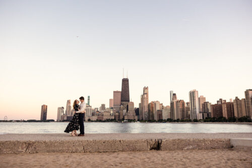 Candid photo of couple standing in front of Chicago skyline during their engagement session at North Avenue Beach