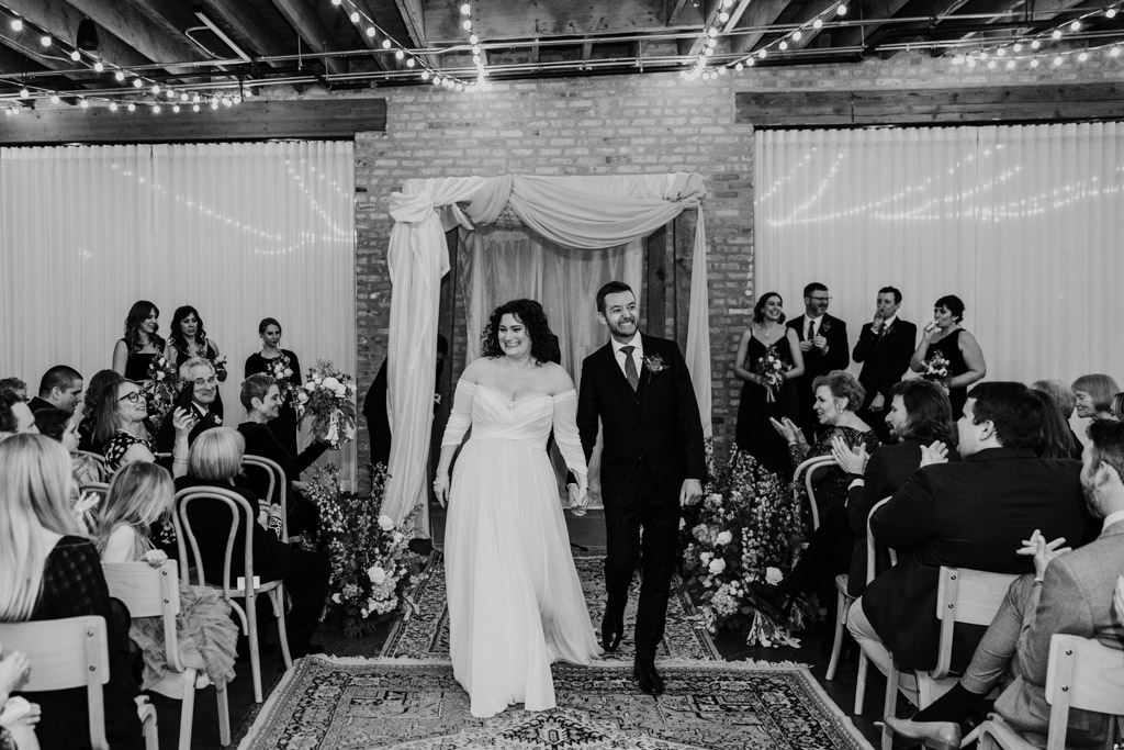 Happy bride and groom walk down the aisle after their winter wedding at The Arbory in Chicago