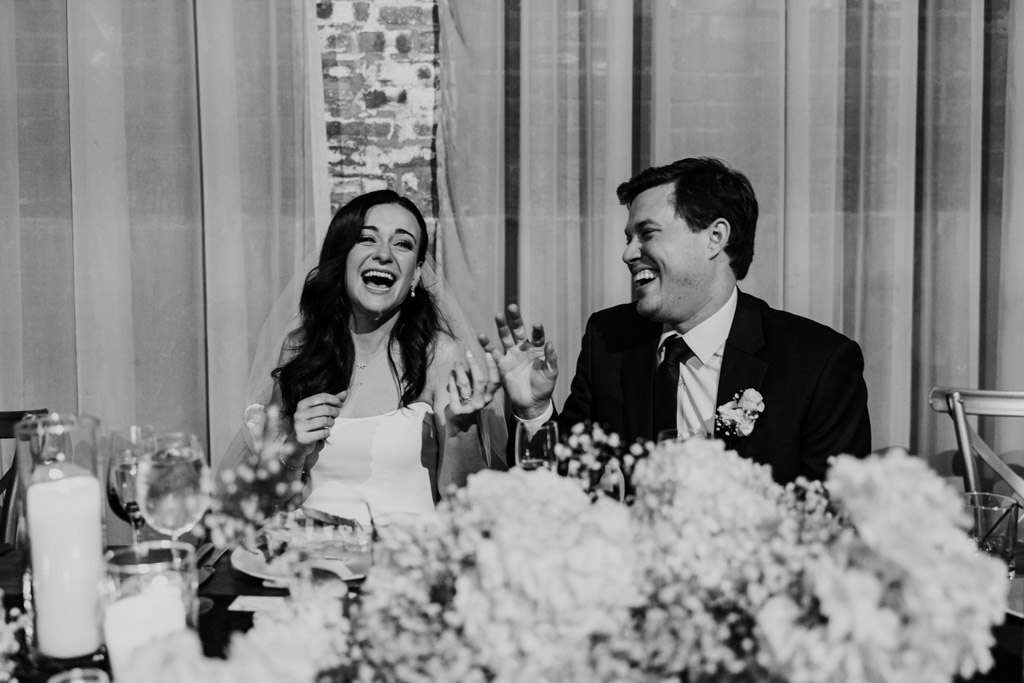 Candid photo of bride and groom laughing at head table during speeches at their winter Fairlie wedding