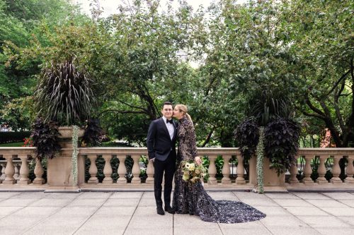 Bride in black dress kisses groom in black tuxedo outside Art Institute of Chicago before their Cindy's Rooftop wedding