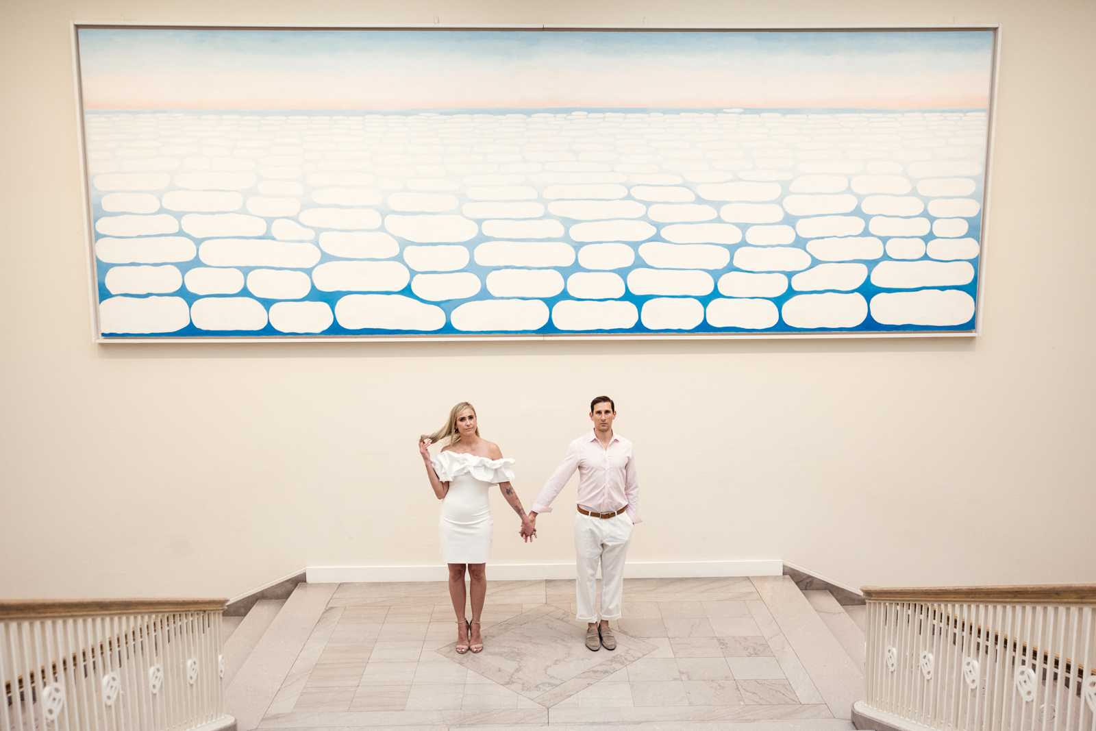 Bride and groom stand on staircase at Art Institute of Chicago with Georgia O'Keefe painting by documentary wedding photographer Emma Mullins Photography
