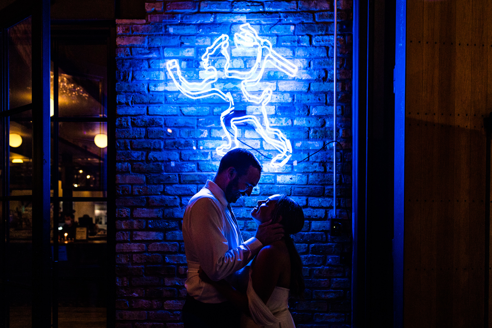 Romantic silhouette of bride and groom with blue neon sign at The Dawson by Chicago wedding photographer Emma Mullins Photography