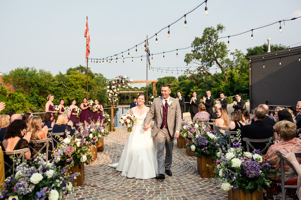 Just married bride and groom walk down the aisle during their summer outdoor Rockwell on the River wedding ceremony