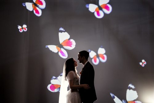 Romantic silhouette of bride and groom in front of butterflies on projection screen at Wildman BT wedding in Chicago