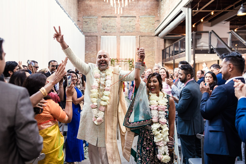 Just-married bride and groom exit their Hindu wedding ceremony while guests cheer at Fairlie Chicago