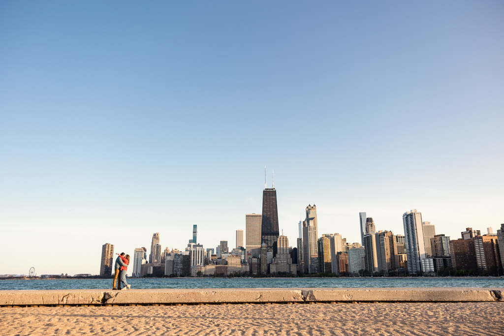 Romantic photo of couple hugging at North Avenue Beach with skyline view during their Chicago spring engagement session