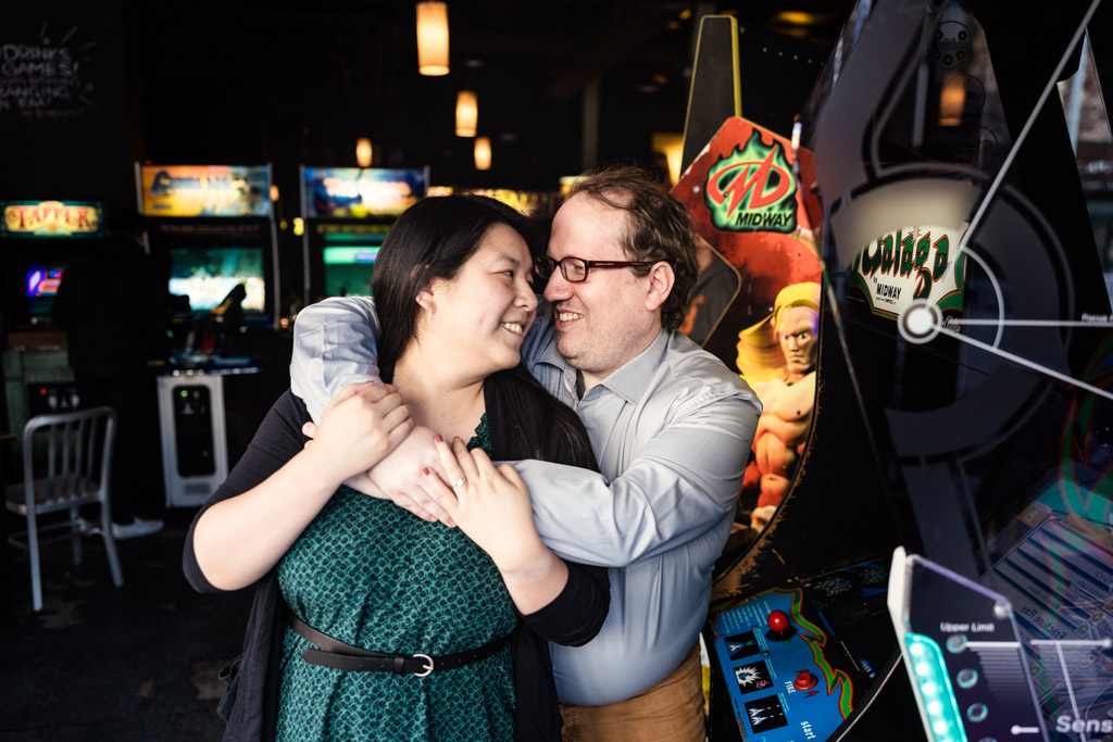 Romantic photo of couple getting cozy in arcade bar next to video game machine during Jersey City engagement session