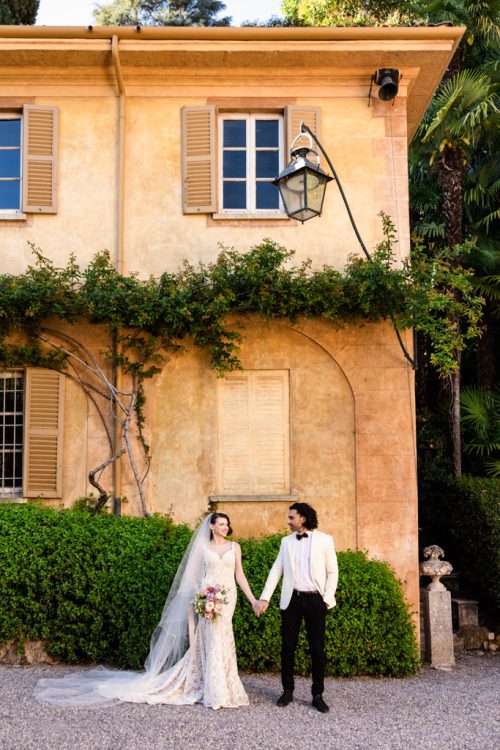 Bride and groom hold hands outside historic Villa Pizzo during their spring Lake Como, Italy wedding