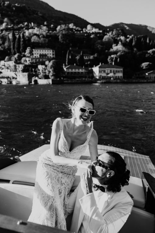 Candid photo of bride and groom laughing in wooden boat on Lake Como after their Italy elopement