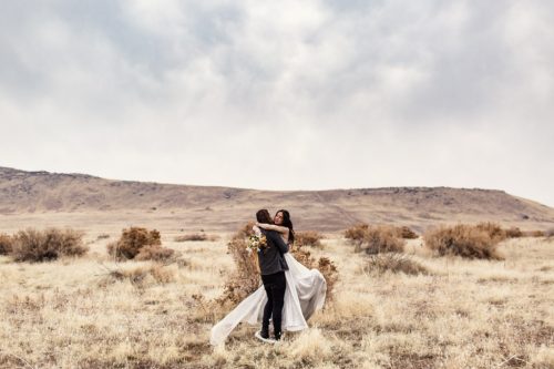 Groom lifts bride for a twirl at their intimate Antelope Island elopement on mountain in Utah