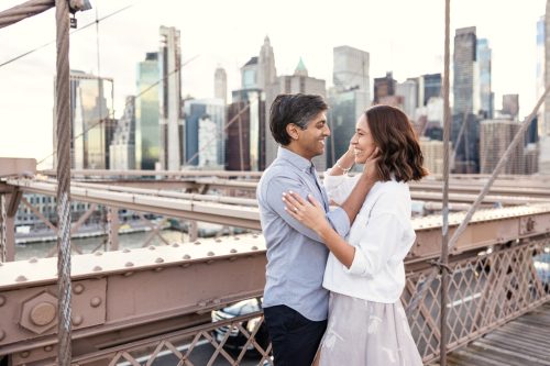 Romantic photo of couple on Brooklyn Bridge with Manhattan skyline view during NYC engagement session