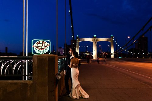 Romantic night photo of bride and groom on Hennepin Bridge with Grain Belt Beer neon sign on their downtown Minneapolis wedding day