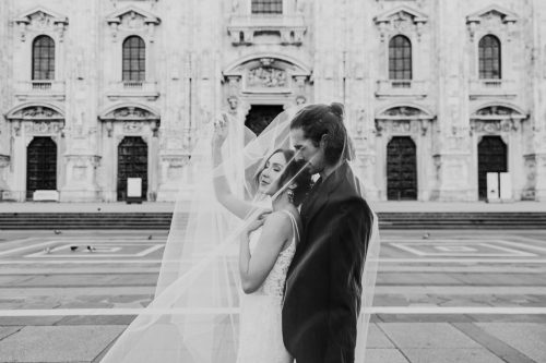 Romantic black and white photo of bride and groom in front of Milan Cathedral after Italy destination wedding
