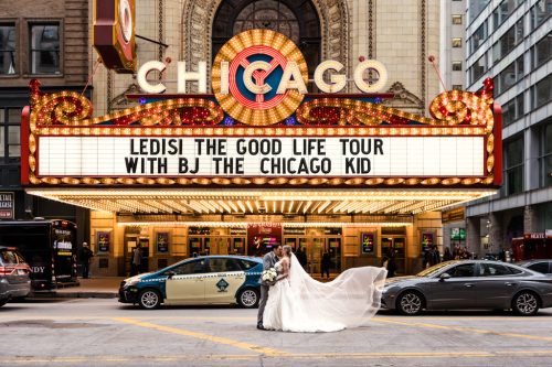 Photo of bride and groom in front of Chicago Theatre with flowing veil