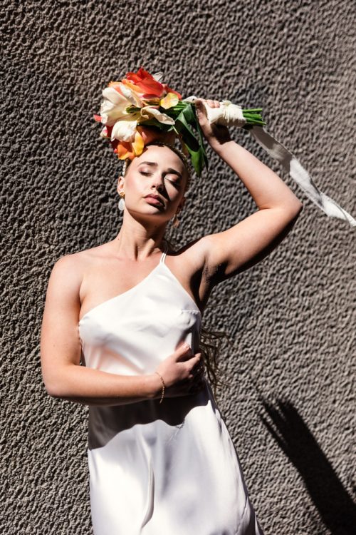 Fashion portrait of bride in Italian street with colorful tulip bouquet after morning elopement in Lake Como