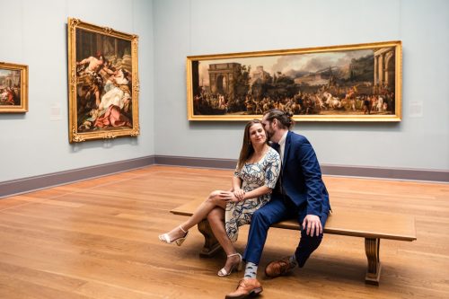 Romantic photo of couple sitting in gallery of Metropolitan Museum of Art during spring engagement session