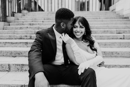 Candid black and white photo of stylish bride and groom on steps of Museo 900 after their destination Italy wedding in Milan
