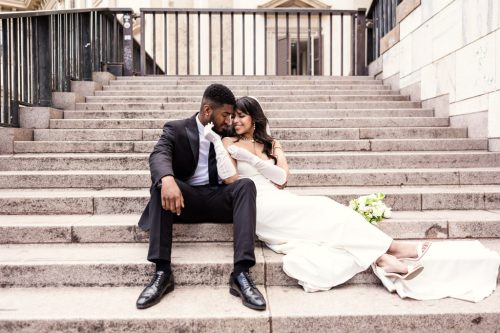 Romantic photo of stylish bride and groom on steps of Museo del Novecento in Milan