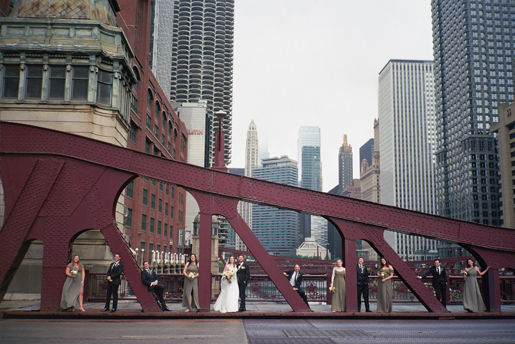 Wedding party stands on LaSalle Bridge with downtown Chicago skyline and fog captured on film
