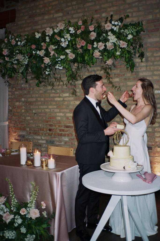Film photo of bride and groom feeding each other wedding cake at their Arbory Chicago wedding reception