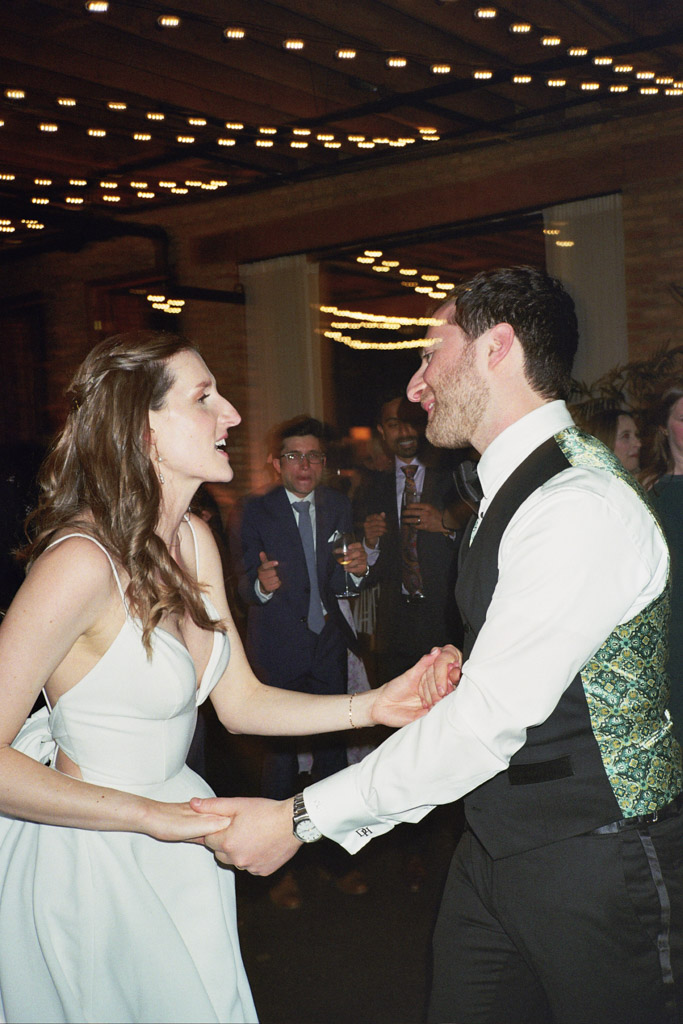 Candid photo of bride and groom dancing under string lights during their Arbory Chicago wedding reception captured on film