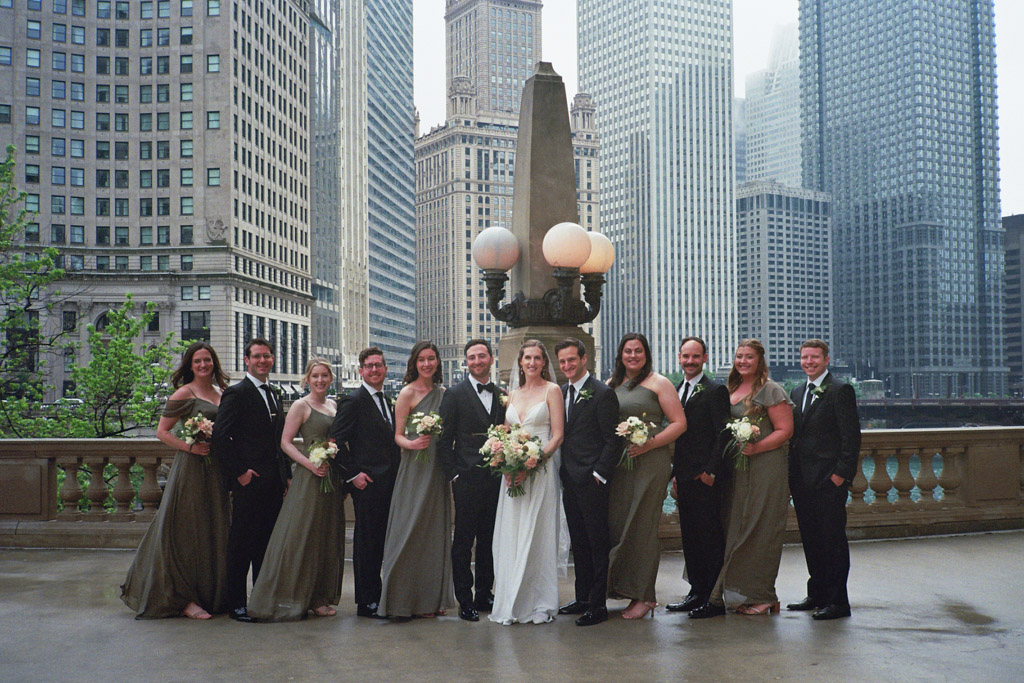 Wedding party stands outside Wrigley Building overlooking Chicago River captured on film
