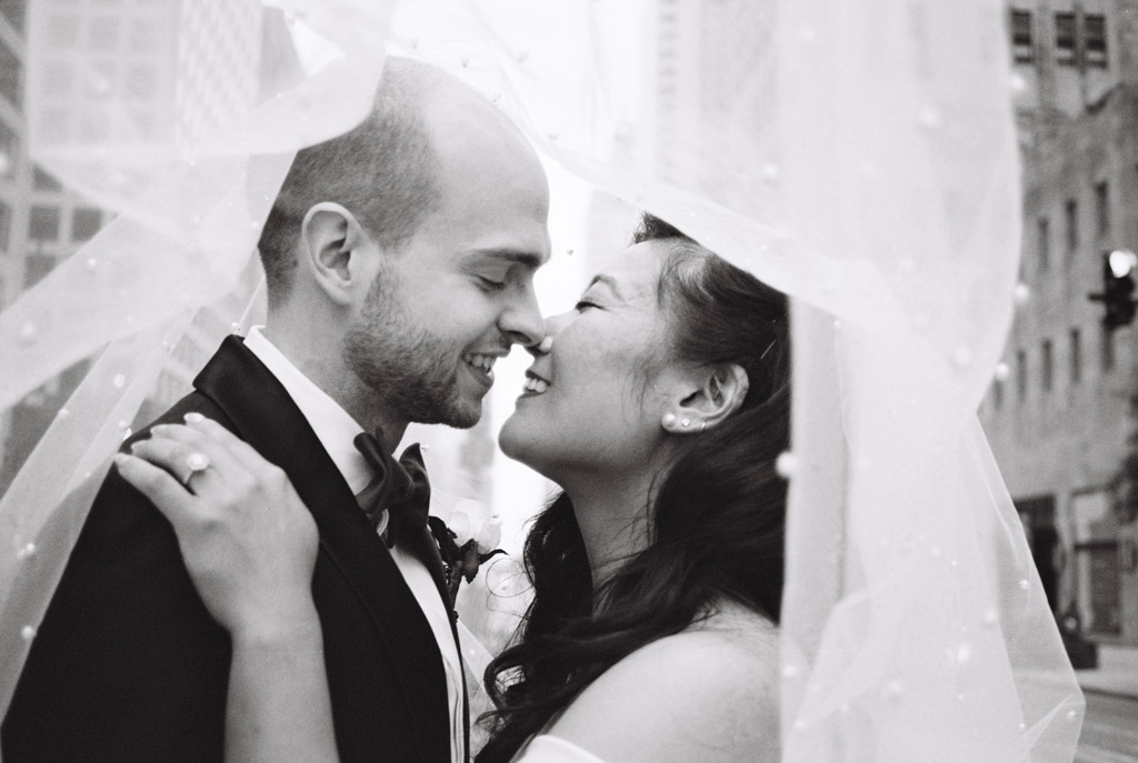 Romantic black and white photo of bride and groom under veil in downtown Chicago