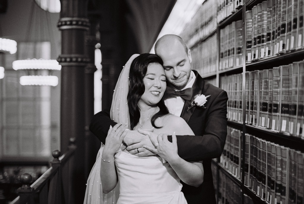Romantic photo of couple standing among stacks of books at their Chicago Library wedding captured on black and white film
