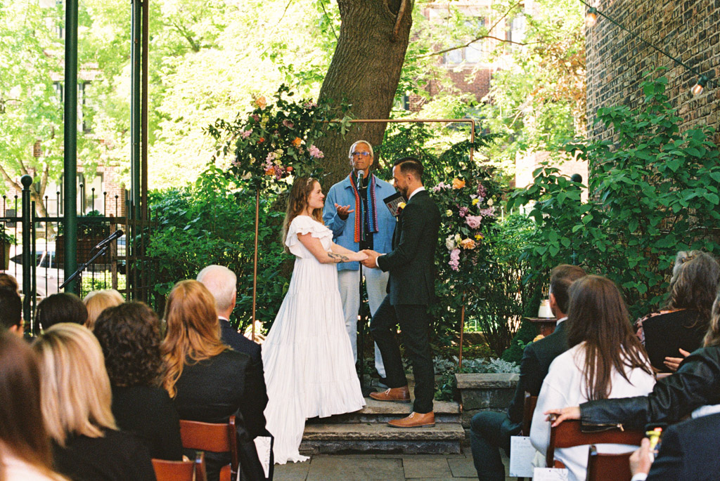 Bride and groom stand at altar during Firehouse Chicago garden wedding ceremony with spring florals