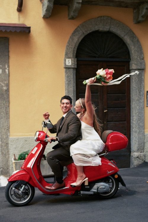 Just married bride and groom ride away on red Vespa after their Italian elopement at Lake Como