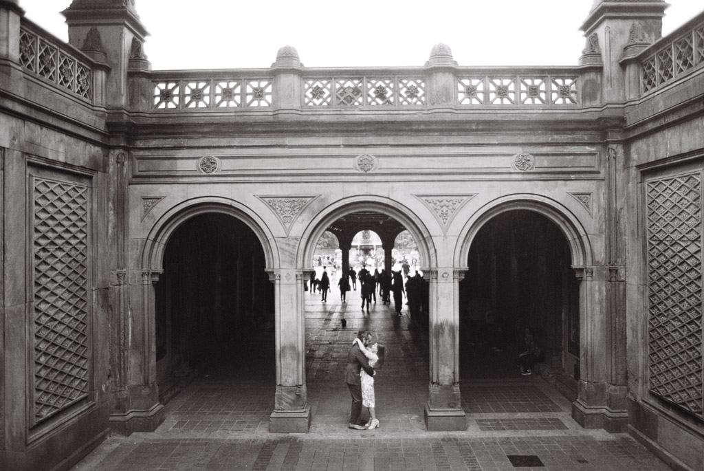 Black and white film engagement photo of couple in archway of Bethesda Terrace in Central Park, New York City