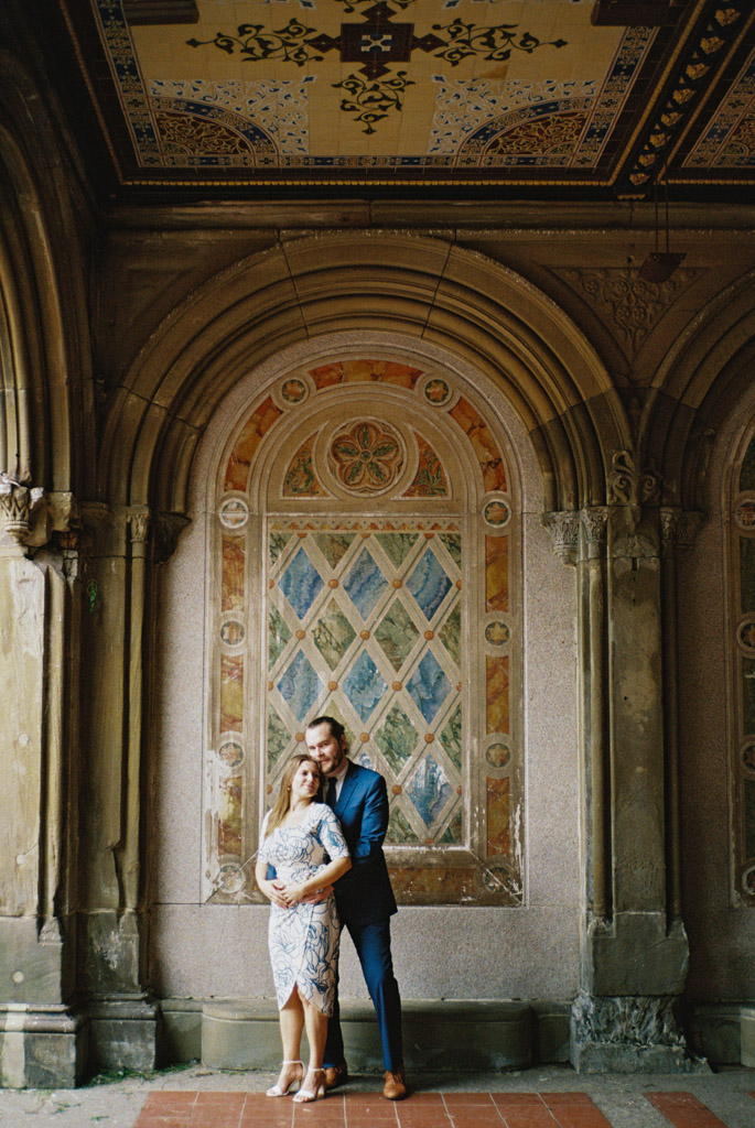 Romantic photo of couple standing in tiled archway at Bethesda Terrace in Central Park during their spring New York City engagement session