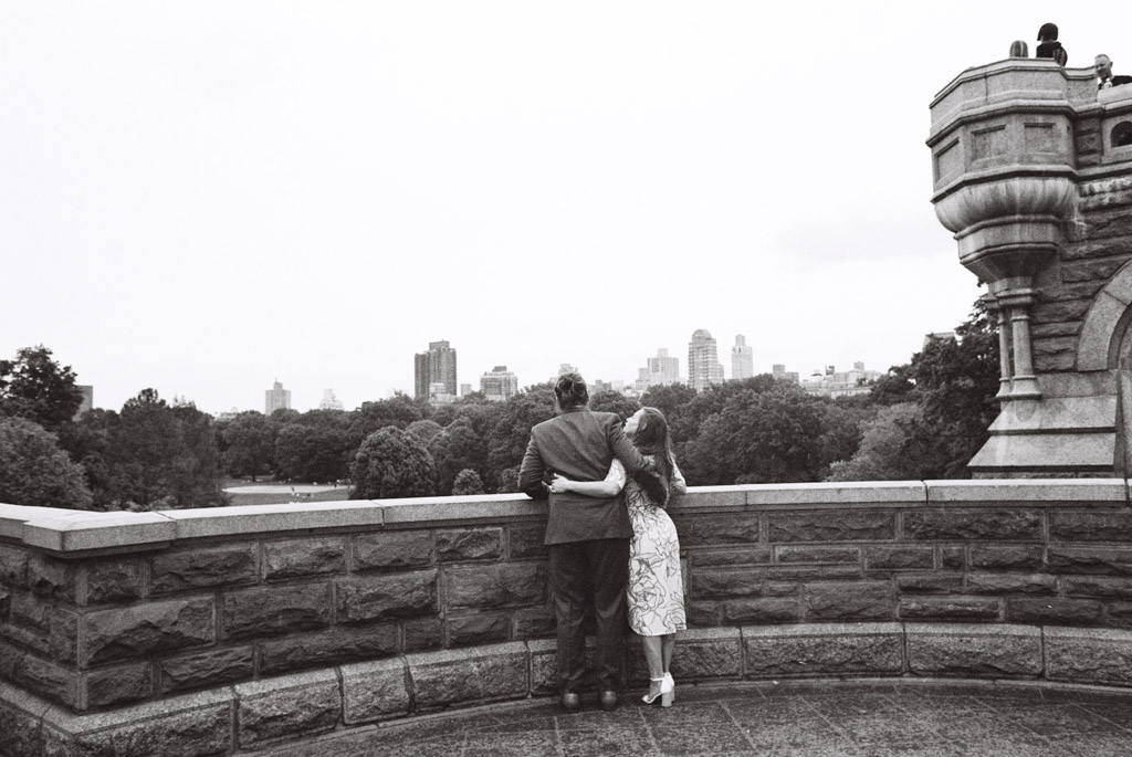 Black and white photo of couple looking out at Turtle Pond from Belvedere Castle in Central Park during their NYC engagement session captured on film