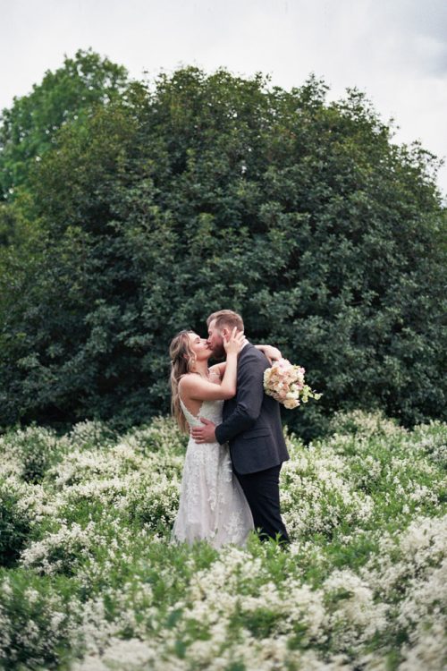 Bride and groom embrace in flower garden at Parco Sempione in Milan, Italy