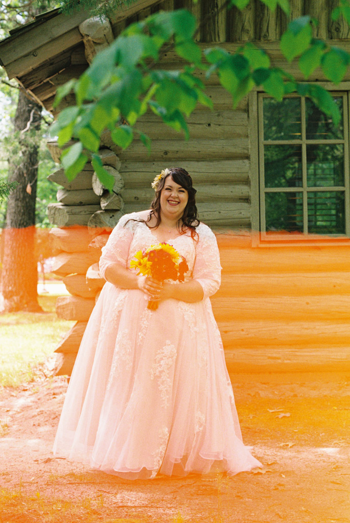 Happy bride stands in front of cabin at Starved Rock State Park elopement captured on film