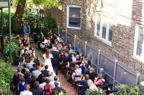 View from balcony of bride and father entering Firehouse Chicago wedding ceremony in outdoor garden space
