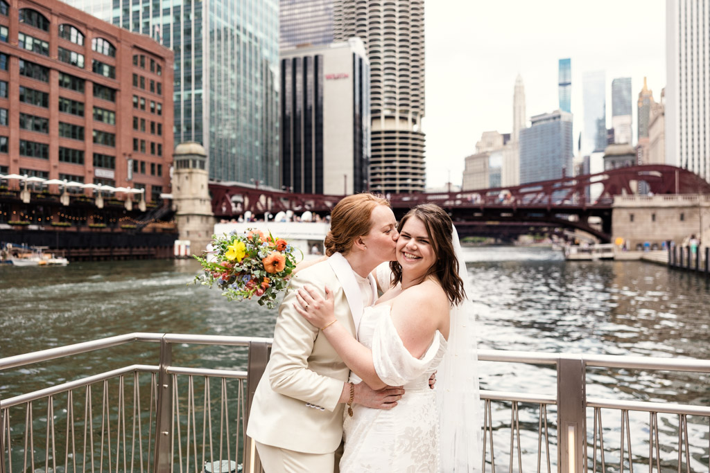 Happy brides get cozy on Chicago Riverwalk after The Rookery Building spring wedding photos