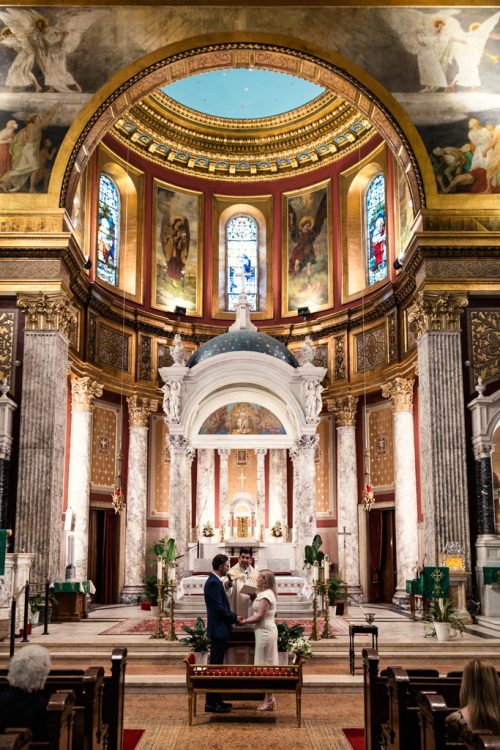 Bride and groom exchange rings in Chicago St. Mary of the Lake cathedral during intimate wedding ceremony