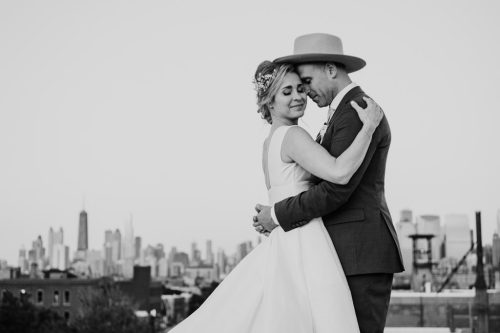 Black and white photo of newlyweds embracing on the roof of The Hive on Hubbard