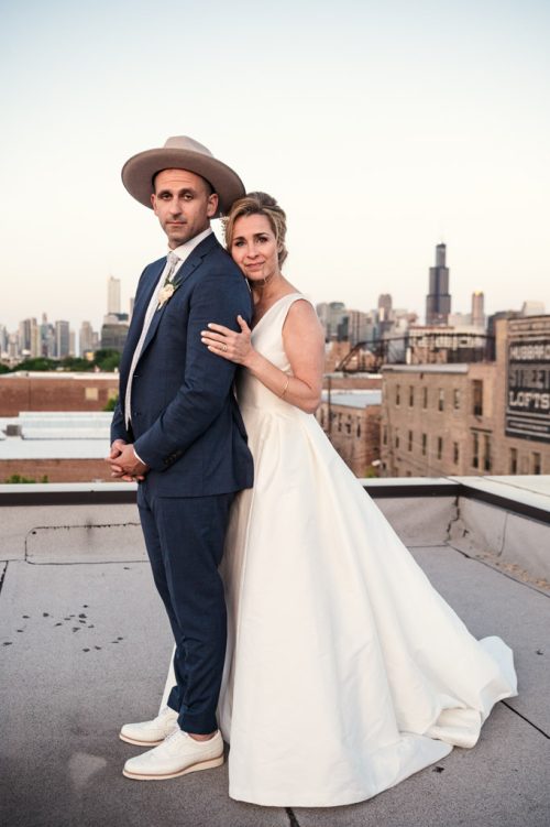 Stylized photo of bride and groom on rooftop with skyline view after their Chicago loft wedding ceremony