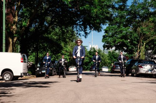 Groom and groomsmen riding scooters before wedding celebration at The Hive on Hubbard in Chicago