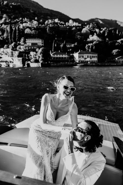 Candid photo of bride and groom laughing in wooden boat on Lake Como after their Italy elopement