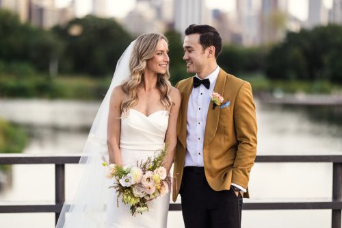 Bride and groom smiling at each other in Lincoln Park with Chicago cityscape in the background