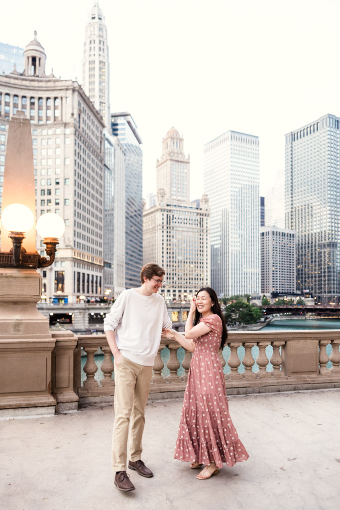 Engaged couple stands near the Chicago River with downtown skyscrapers in the background