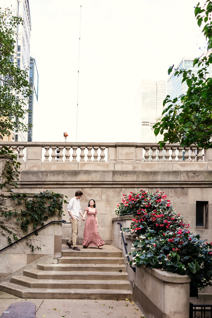 Couple walks down stone staircase at Chicago Riverwalk during sunrise engagement session